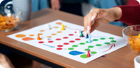 Spelavond met gekleurde pionnen, speelbord en snacks op een houten tafel.